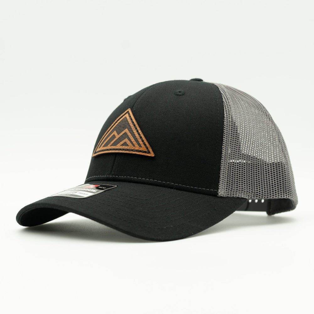 Side view of Dark Mountain leather patch hat on black and charcoal Richardson 115 low profile hat, showing triangle mountain patch, shallow crown, curved bill, and mesh back, a low profile mountain hat for outdoor adventures.

Color: Black/Charcoal