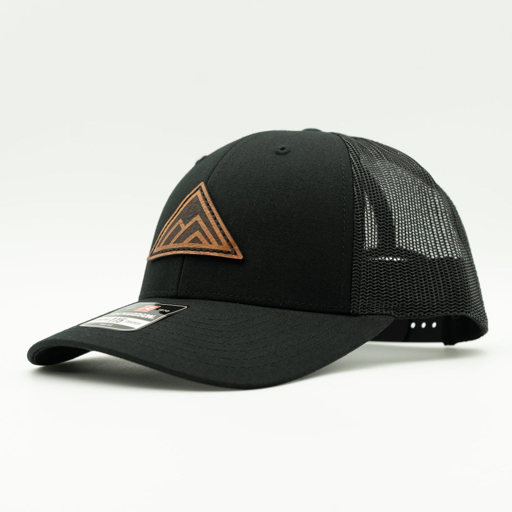 Side view of Dark Mountain leather patch hat on solid black Richardson 115 low profile hat, showing triangle mountain patch, shallow crown, curved bill, mesh back, and snapback, a low profile mountain hat for hiking and casual outfits.

Color: Solid Black