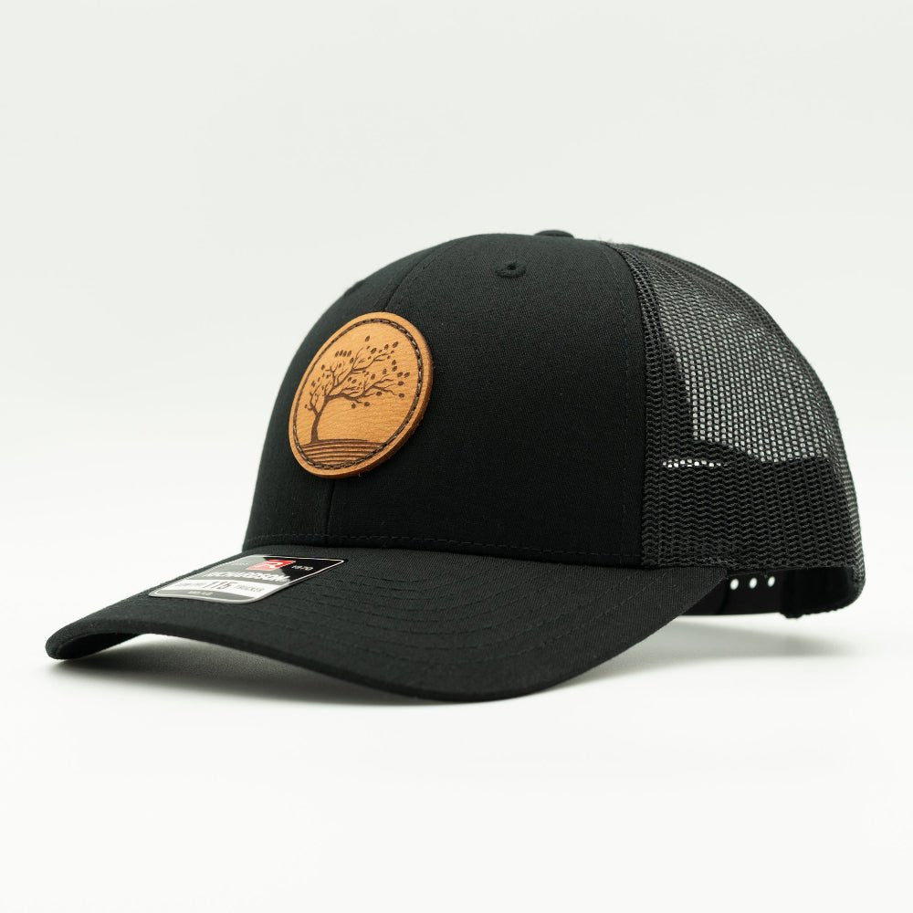 Side view of Black Black Richardson 115 low profile trucker hat with Blossom leather patch, mesh back and curved visor.

Color: Solid Black