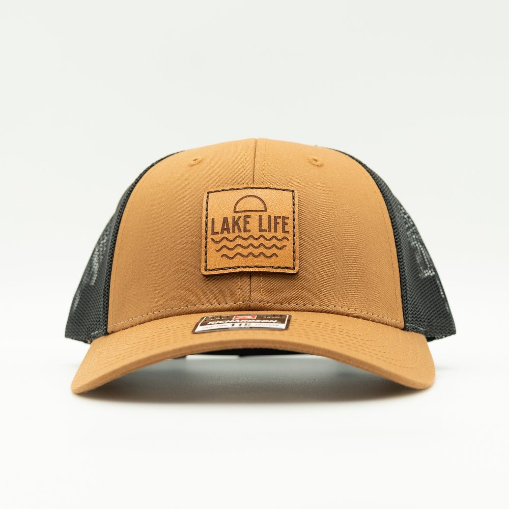 Front view of Lake Life leather patch hat on caramel and black Richardson 115 low profile trucker, with warm caramel bill, leather patch, mesh back, and snapback.

Color: Caramel/Black