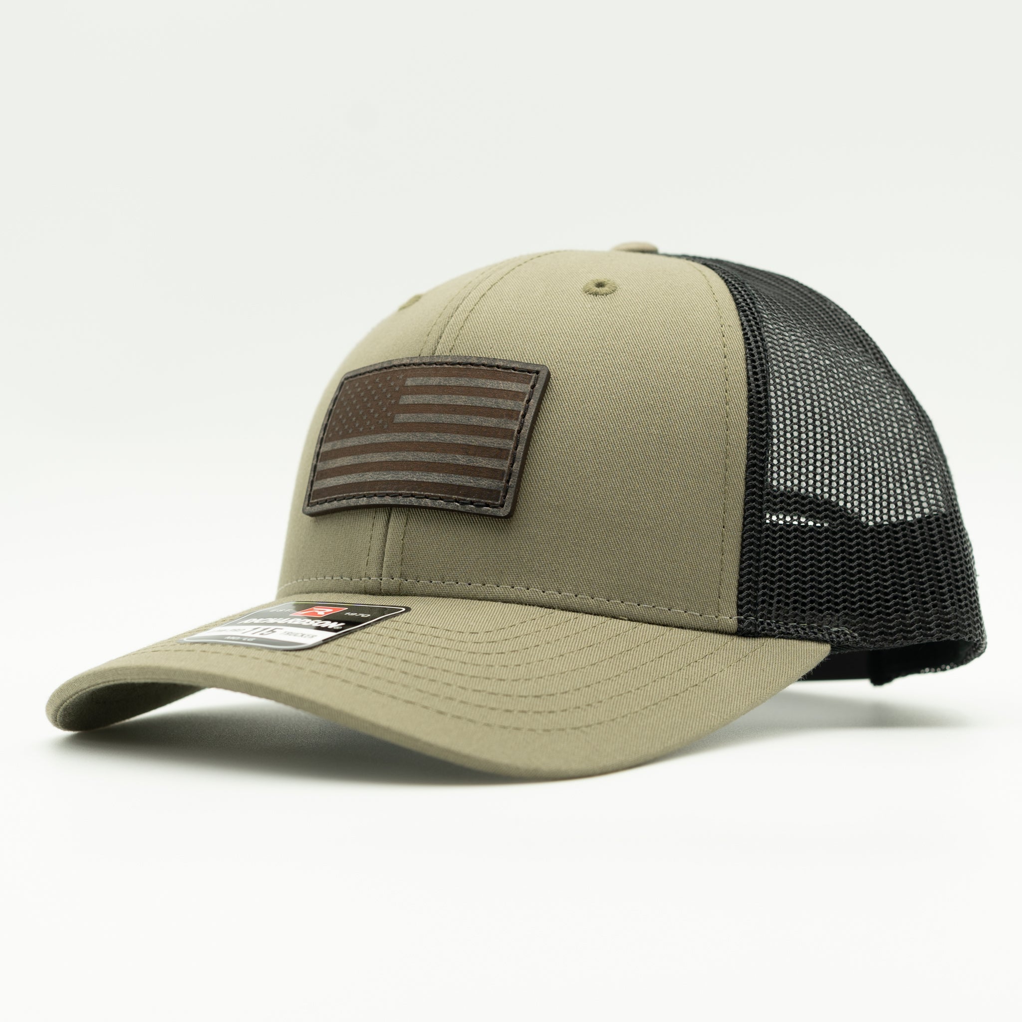 A trucker-style baseball cap in khaki and black mesh, featuring a brown American flag patch on the front and a small brand tag on the brim.

Color: Loden/Black