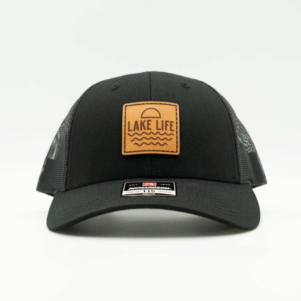 Front view of Lake Life leather patch hat on black and black Richardson 115 low profile trucker, showing engraved leather patch, curved bill, mesh back, and snapback.

Color: Solid Black