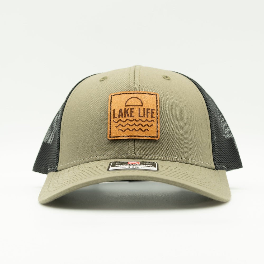 Front view of Lake Life leather patch hat on loden and black Richardson 115 low profile trucker, showing leather patch, curved bill, mesh back, and snapback.

Color: Loden/Black