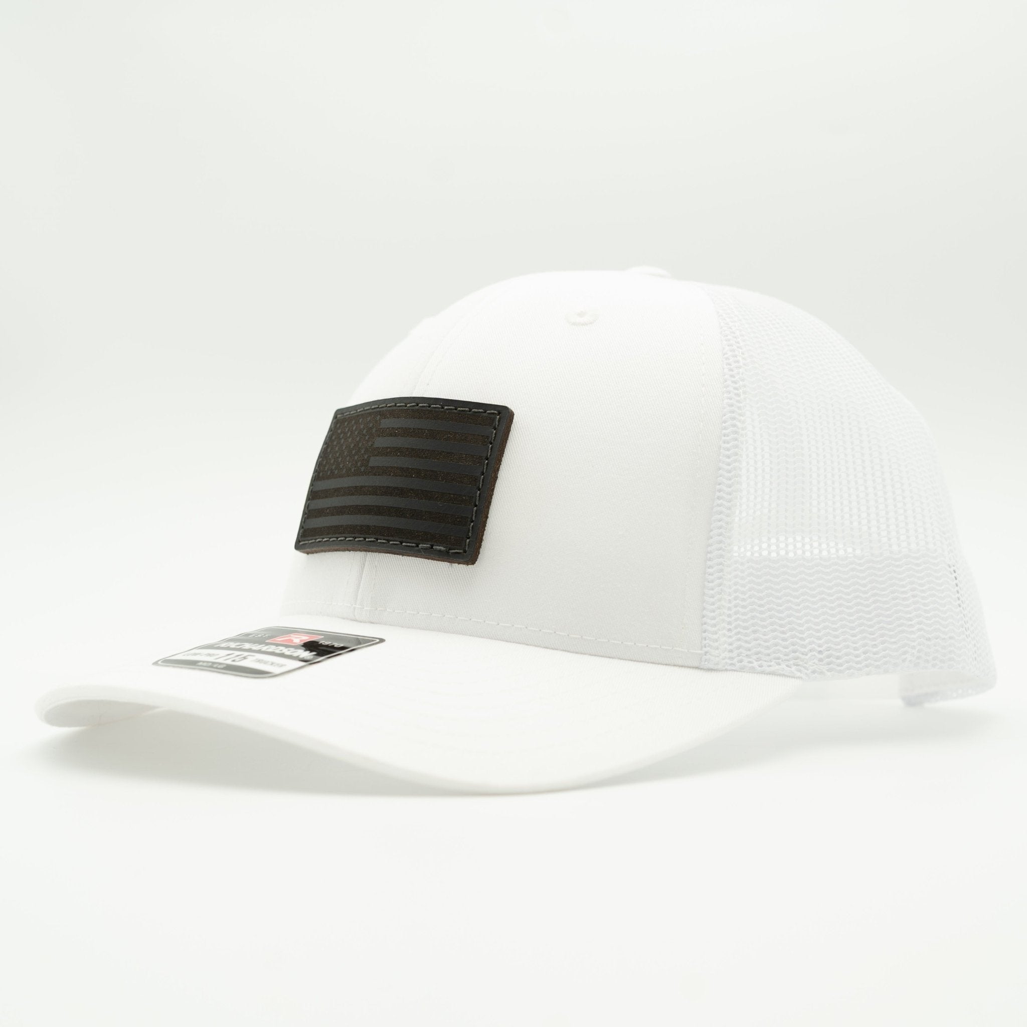 A white trucker-style baseball cap with a black rectangular patch on the front panel, photographed on a clean white background.

Color: Solid White