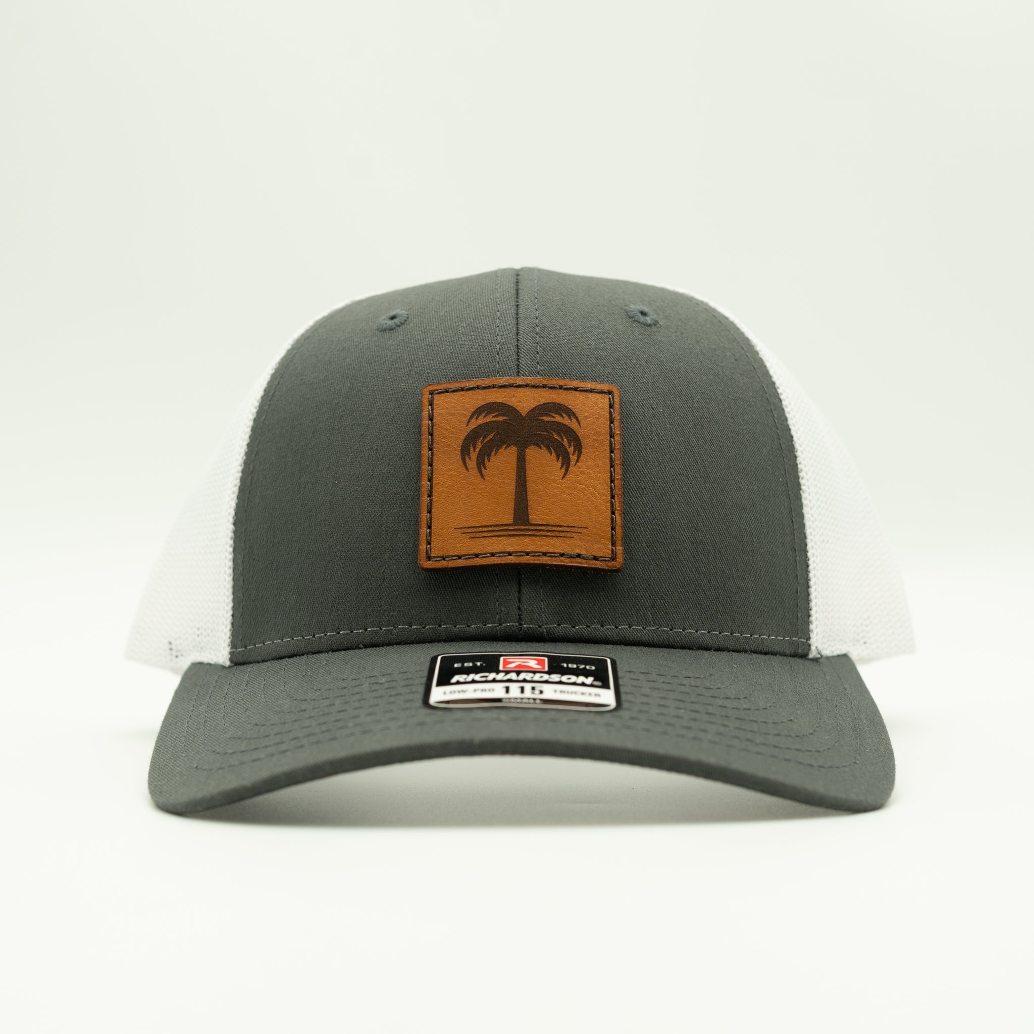 Front view charcoal/white Solo Palm leather patch hat, clean palm tree design on a low profile leather patch trucker for summer adventures.