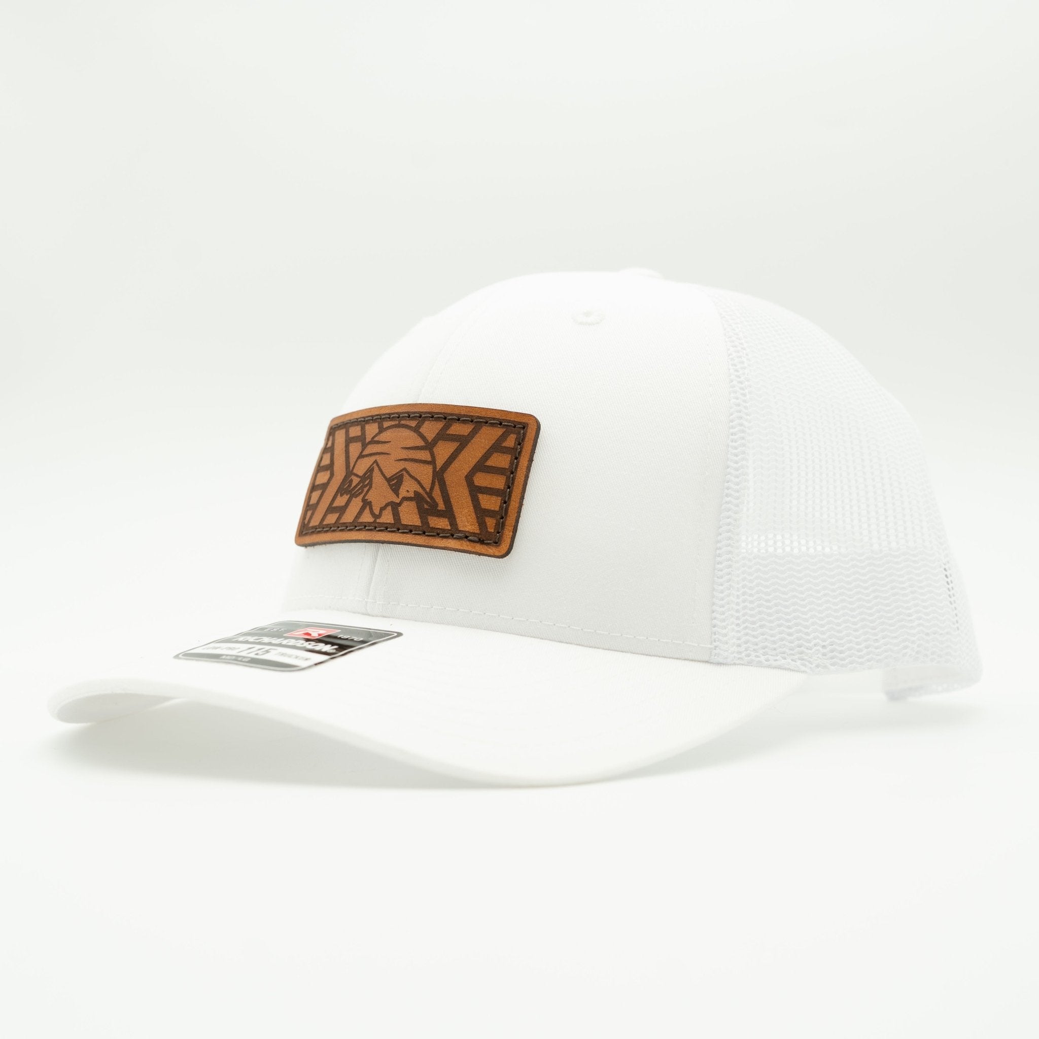 A white trucker-style cap with a brown leather patch on the front featuring a stylized graphic, photographed on a clean white background.

Color: Solid White