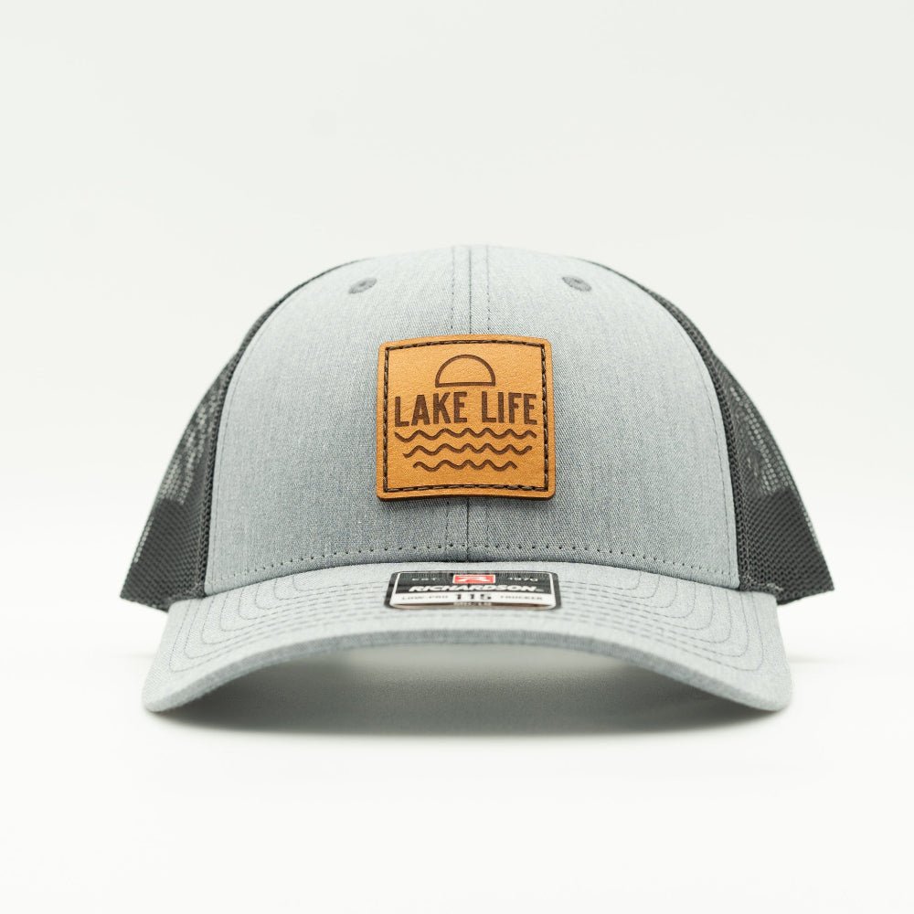 Front view of Lake Life leather patch hat on heather grey and dark charcoal Richardson 115 low profile trucker, showing engraved leather patch, curved bill, mesh back, and snapback.

Color: Heather Grey/Charcoal