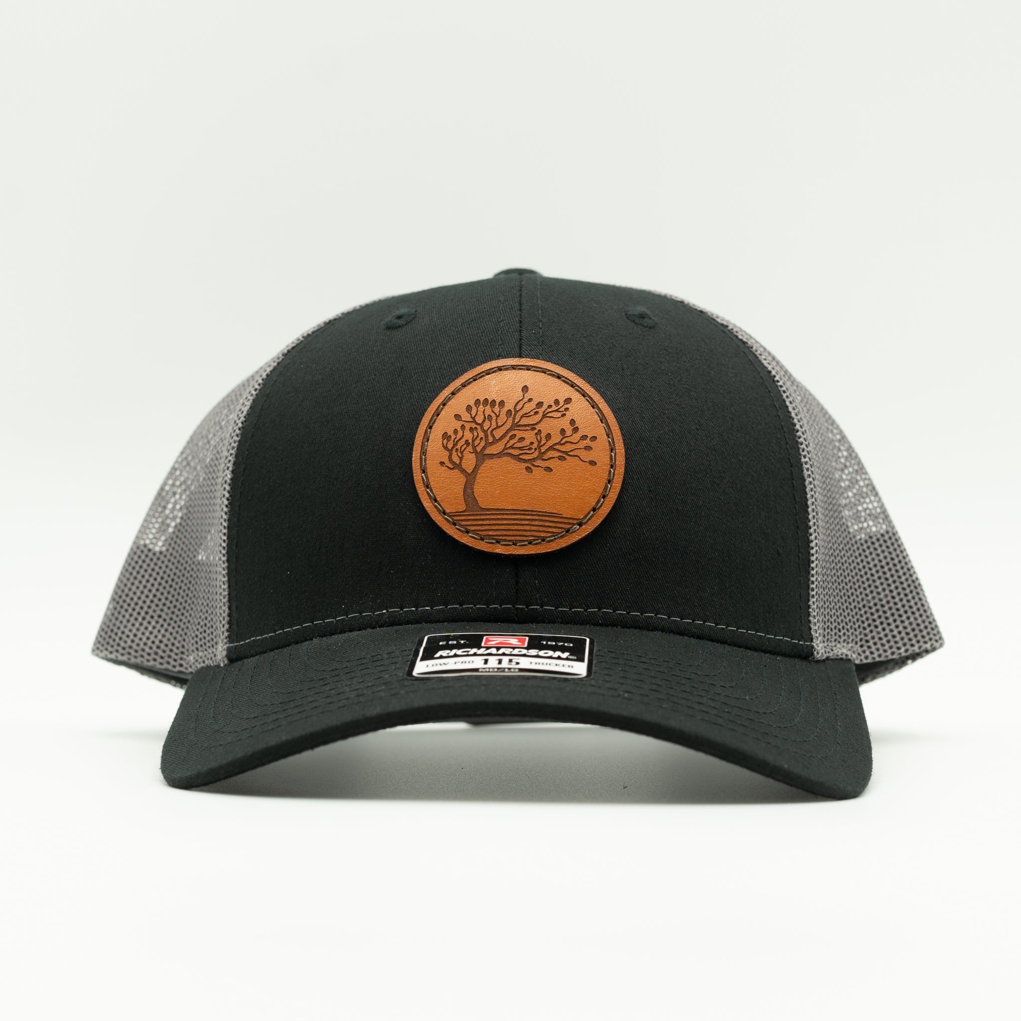 Front view of Black Charcoal Blossom leather patch hat on Richardson 115, low profile crown with curved bill and floral patch.

Color: Black/Charcoal