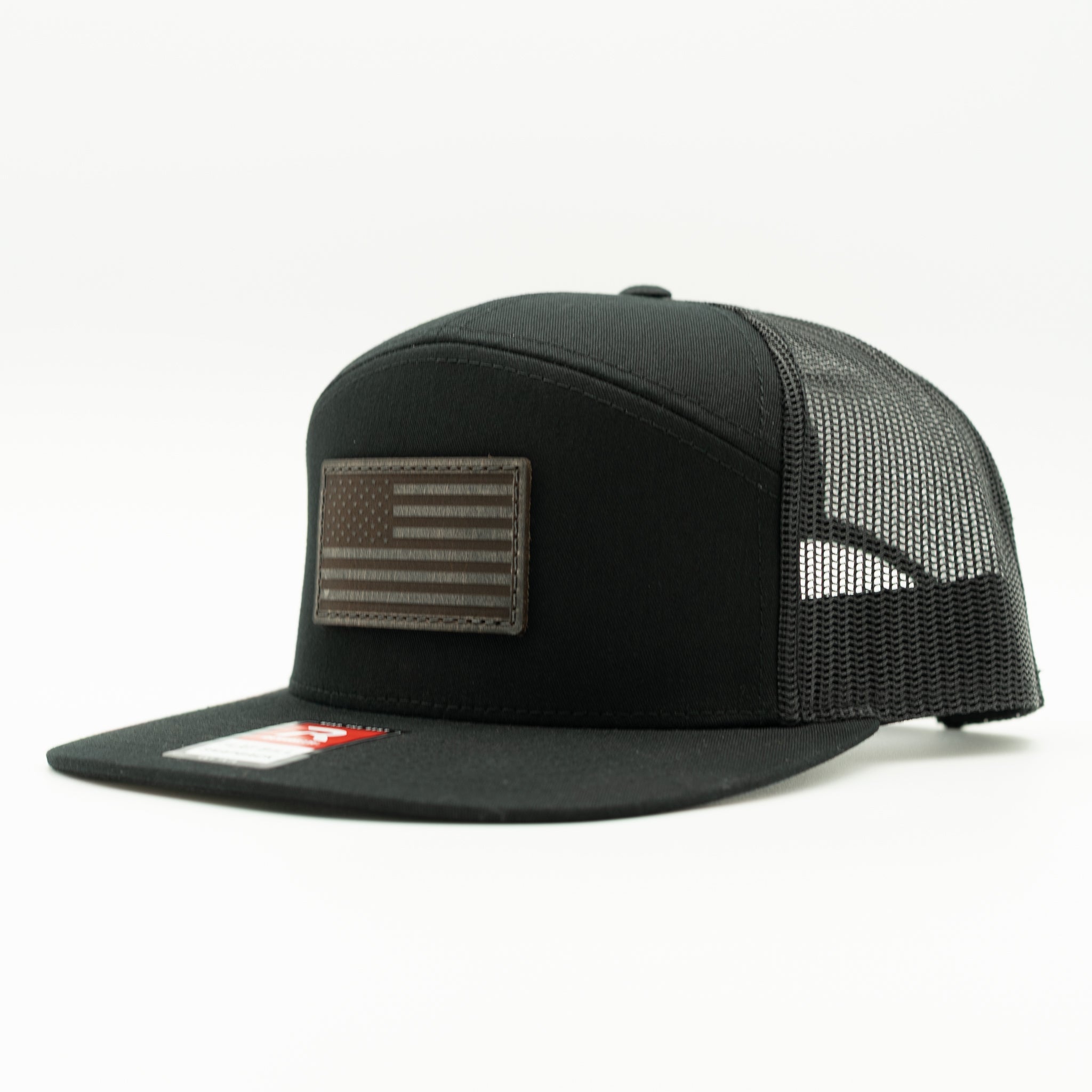 Solid black Richardson 168 flat bill trucker hat with charcoal American Flag leather patch, side view highlighting seven panel crown and mesh back.

Color: Black/Black  168 (OSFM)
