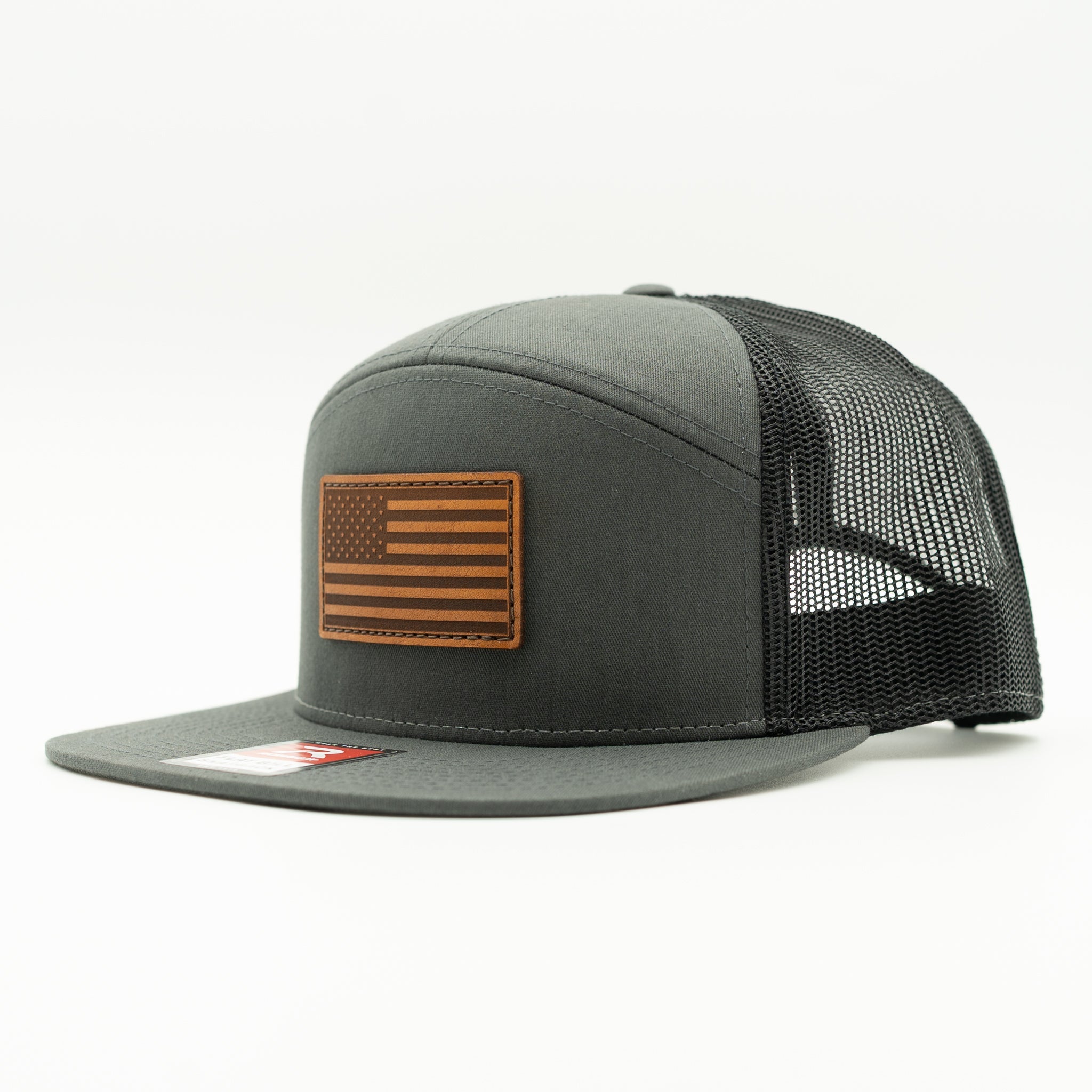 Charcoal and black Richardson 168 seven panel flat bill trucker hat with light brown American Flag leather patch, side view showing mesh back and flat bill.

Color: Charcoal/Black 168 (OSFM)