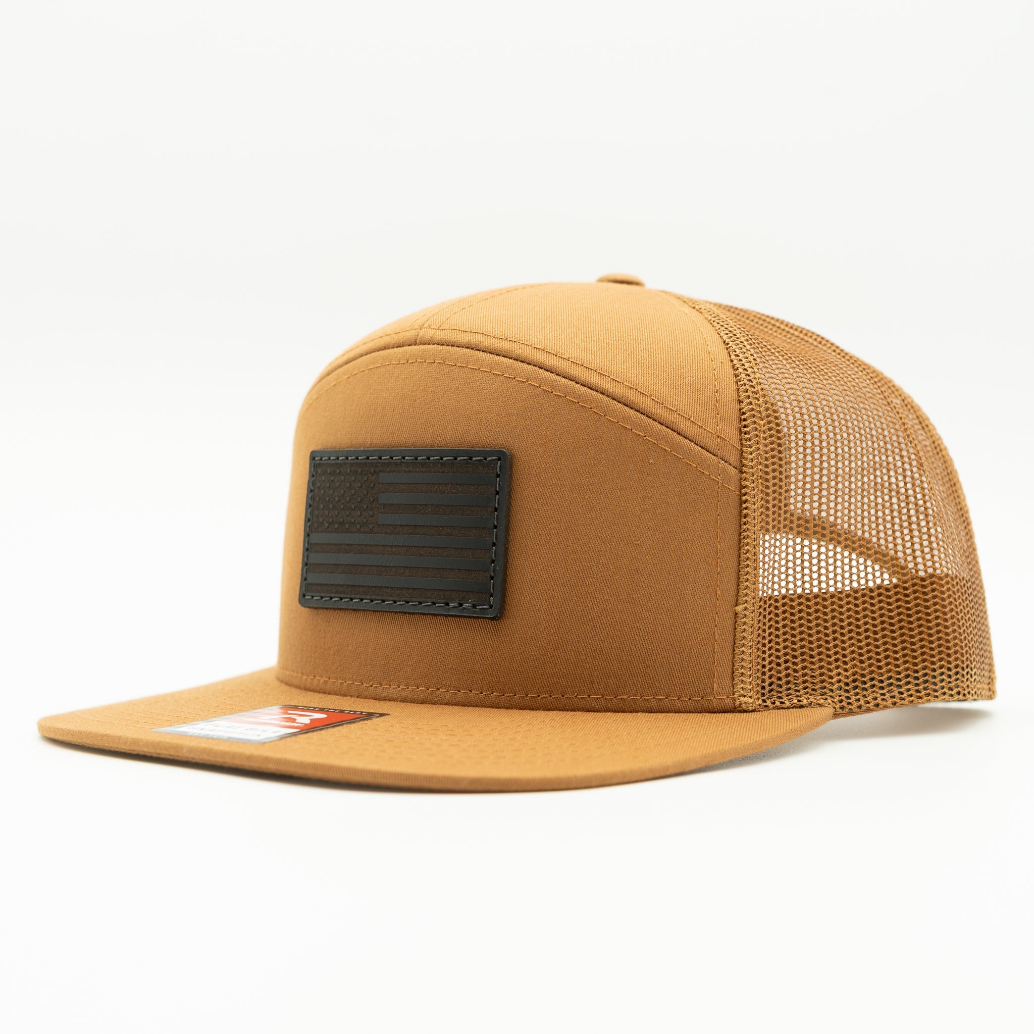 Caramel Richardson 168 seven panel trucker hat with black American Flag leather patch, side view showing flat bill, structured crown, and mesh back.

Color: Caramel 168 (OSFM)