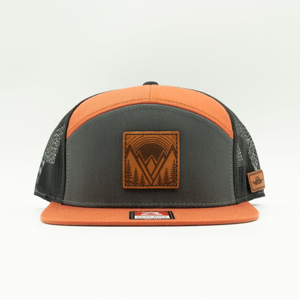 Mountain East leather patch hat on a charcoal, orange, and black Richardson 168 seven panel trucker, front view with orange flat bill, high crown, mesh back, and stitched mountain patch.
