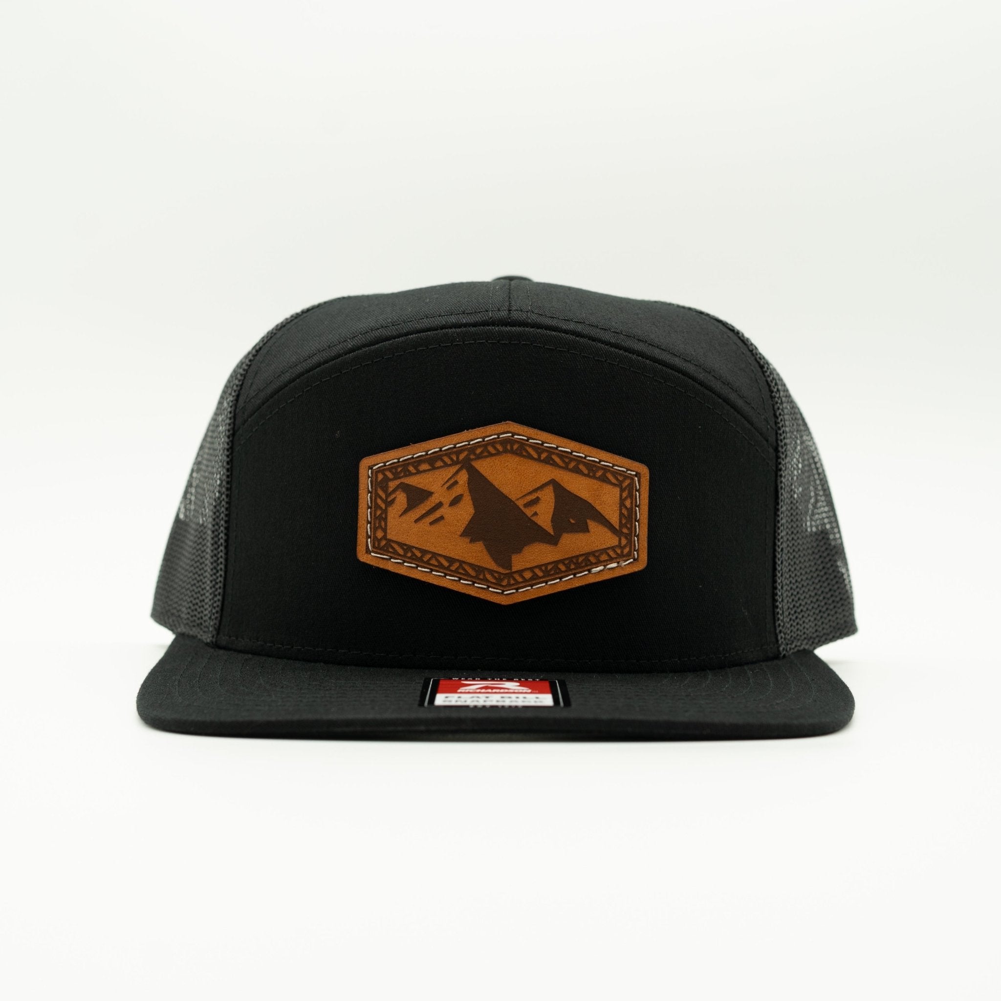 A black trucker-style cap with a brown leather patch featuring a mountain design on the front, set against a plain white background.

Color: Black/Black  168 (OSFM)