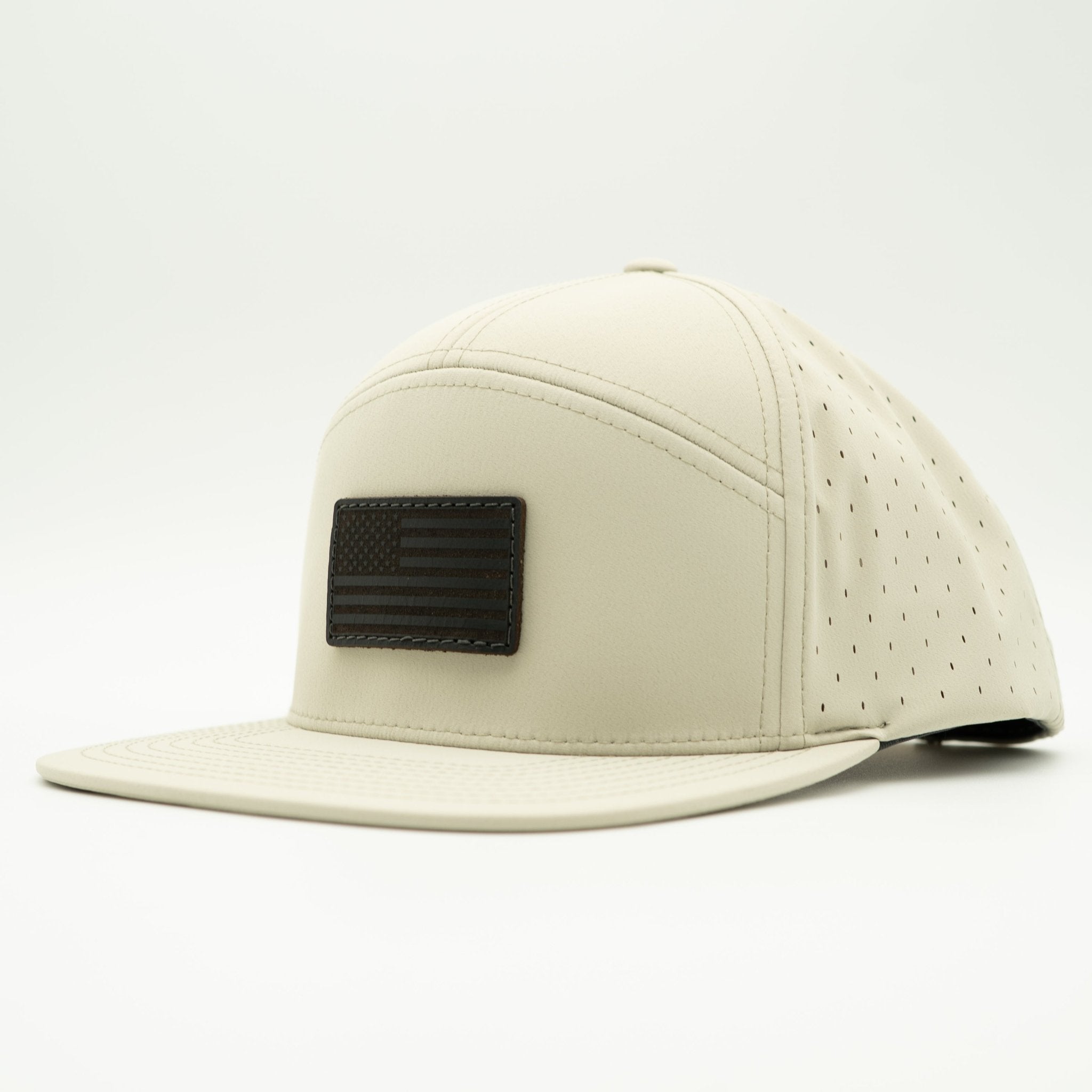 A light beige leather baseball cap with a flat brim, featuring a black rectangular patch with a black American flag design on the front, set against a plain white background.

Color: Ivory