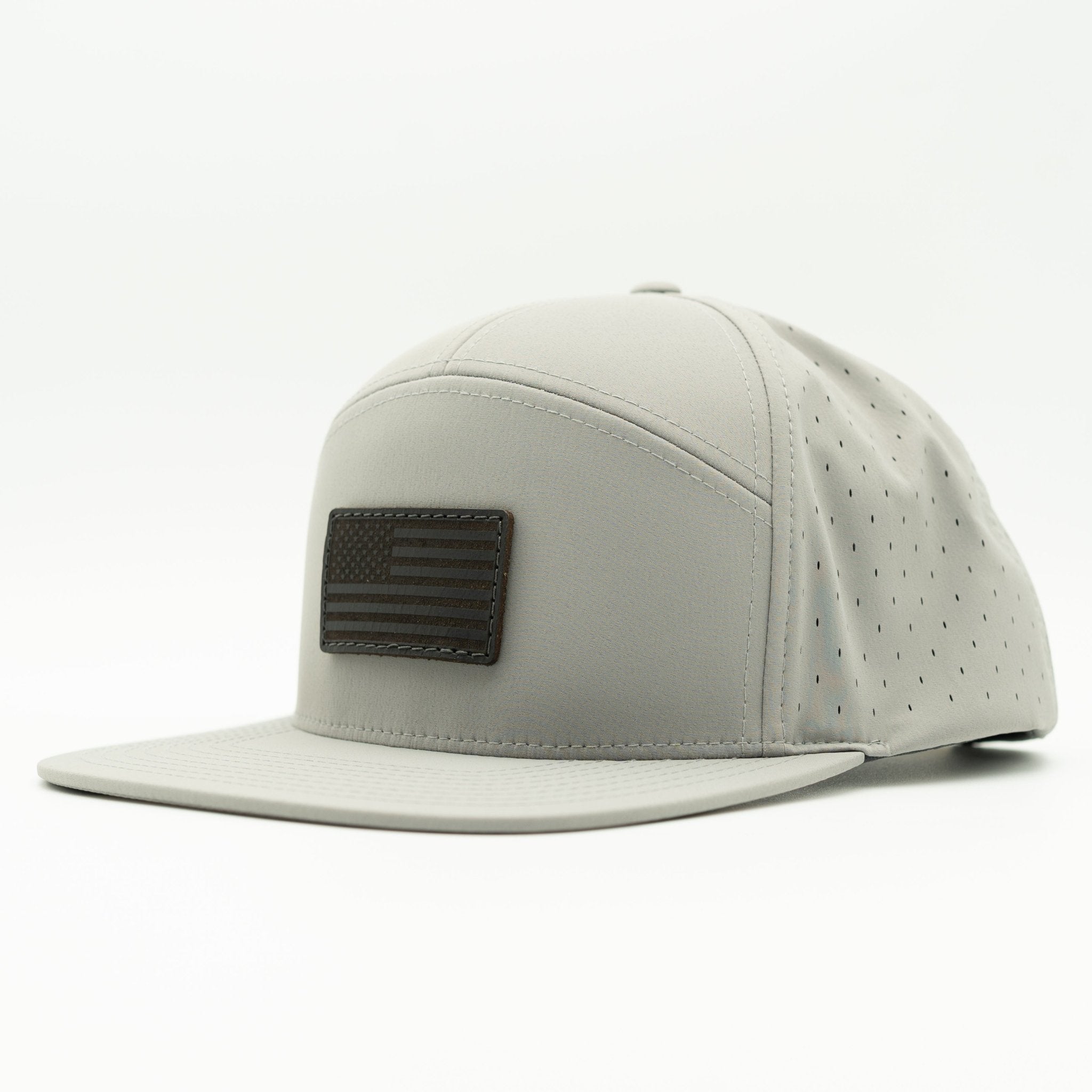 A light gray flat-brim cap with a dark brown leather American flag patch on the front, shown against a plain white background.

Color: Silver