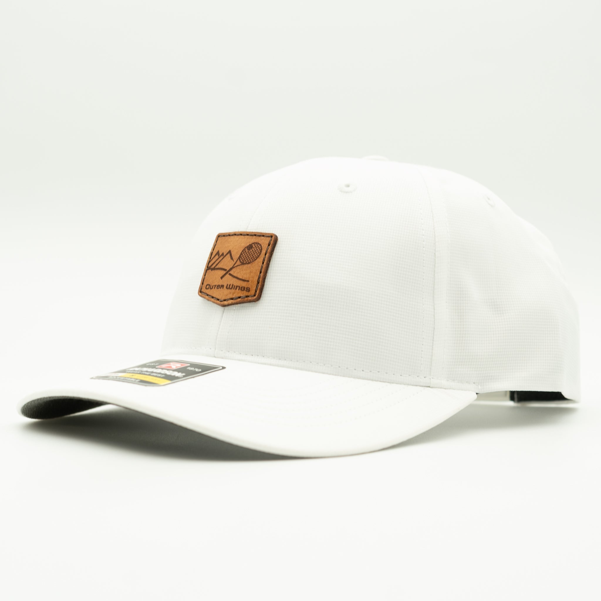 A white baseball cap with a brown leather patch on the front featuring a tennis racket graphic and the text 'Outer Wings'. The cap is photographed on a seamless white studio background.

Color: Solid White