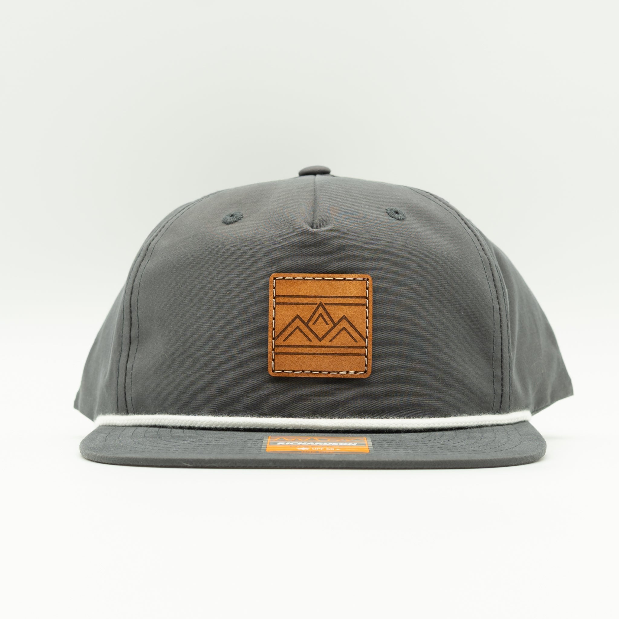 Rustic Ridge charcoal and white Richardson 256 rope hat front view with square veg tan leather mountain patch and clean flat bill.