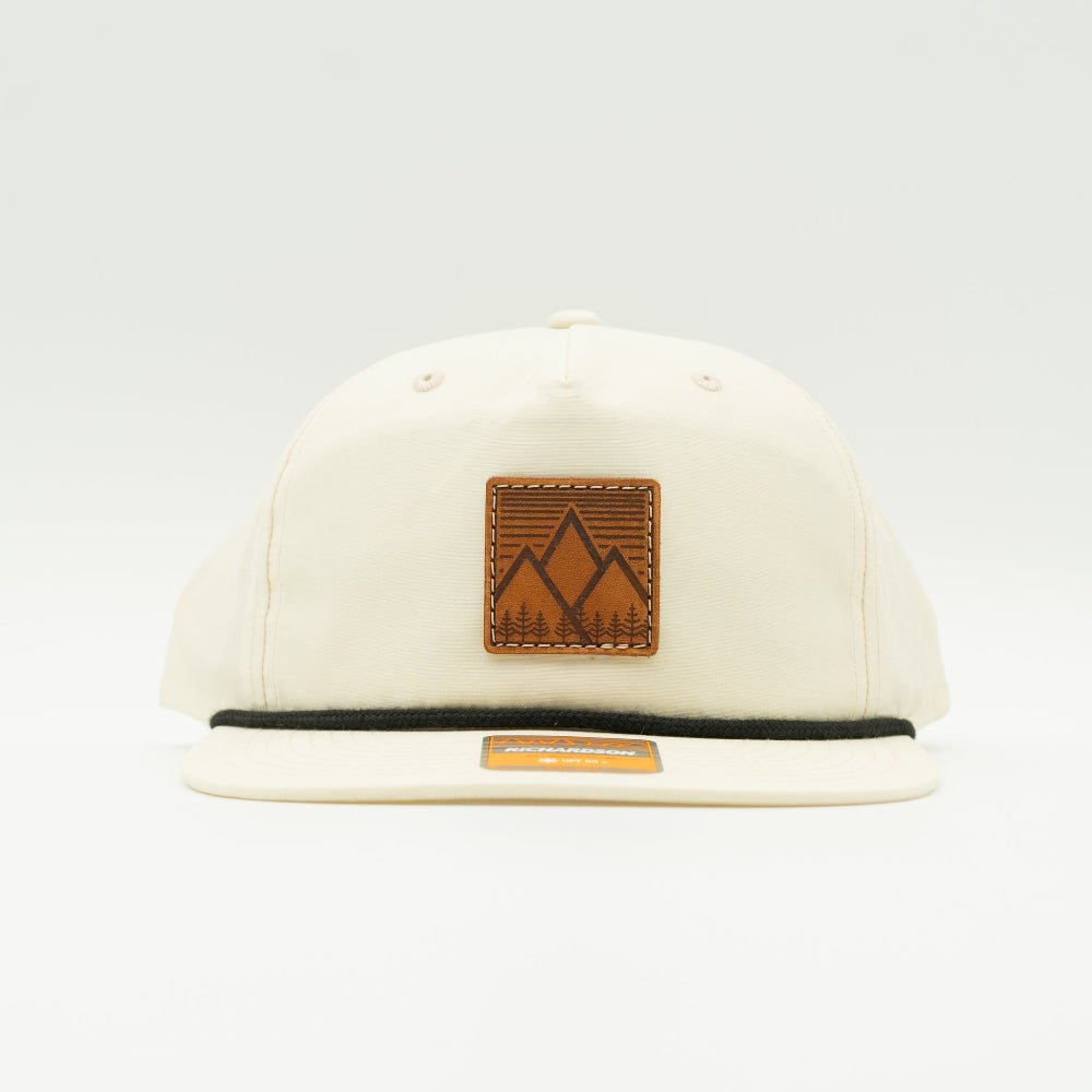 Front view of Mountain West leather patch rope hat on birch Richardson 256, showing square mountain patch, flat bill with rope, and low profile 5-panel crown.