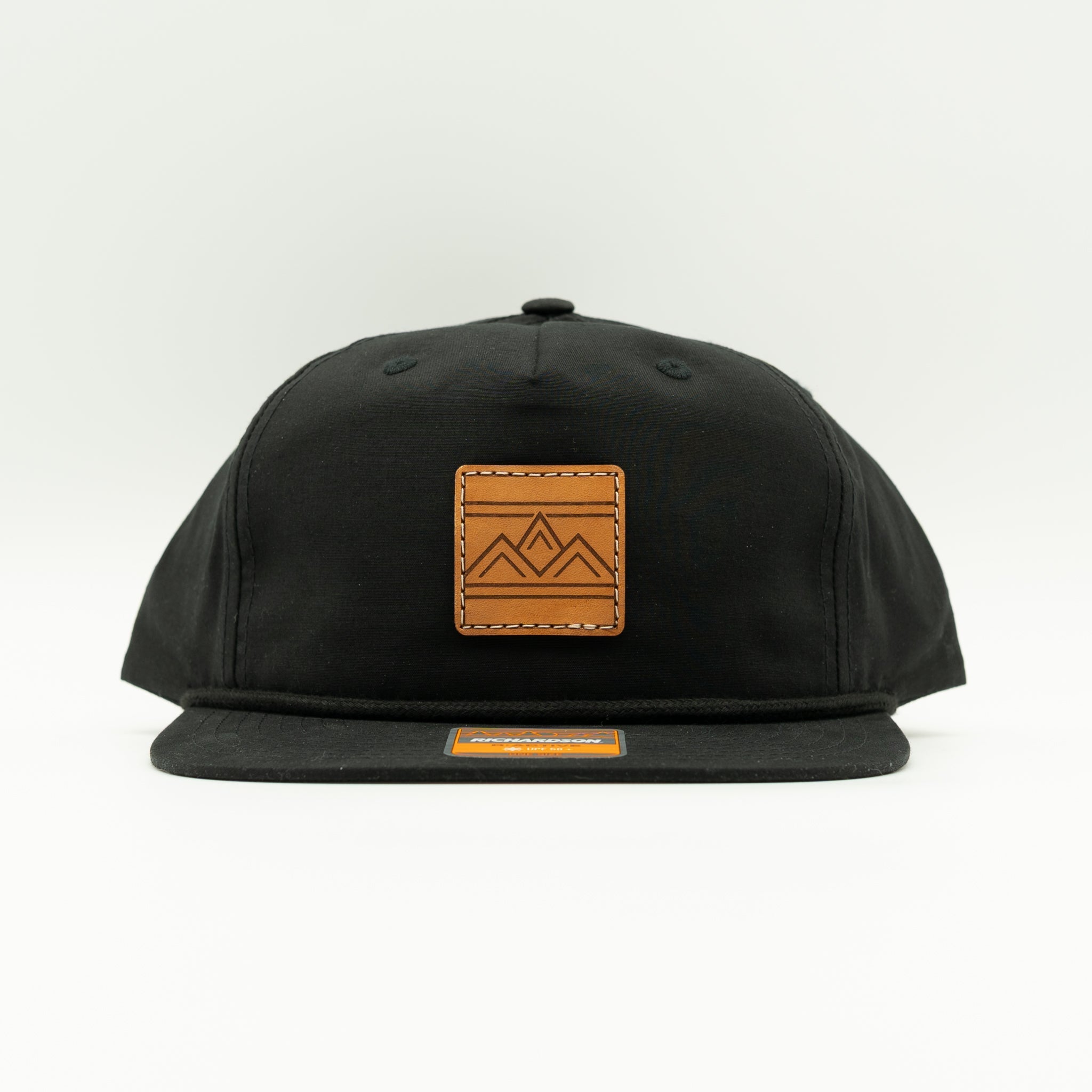 Rustic Ridge black Richardson 256 rope hat front view with square veg tan leather mountain patch, flat bill, and braided rope detail.
