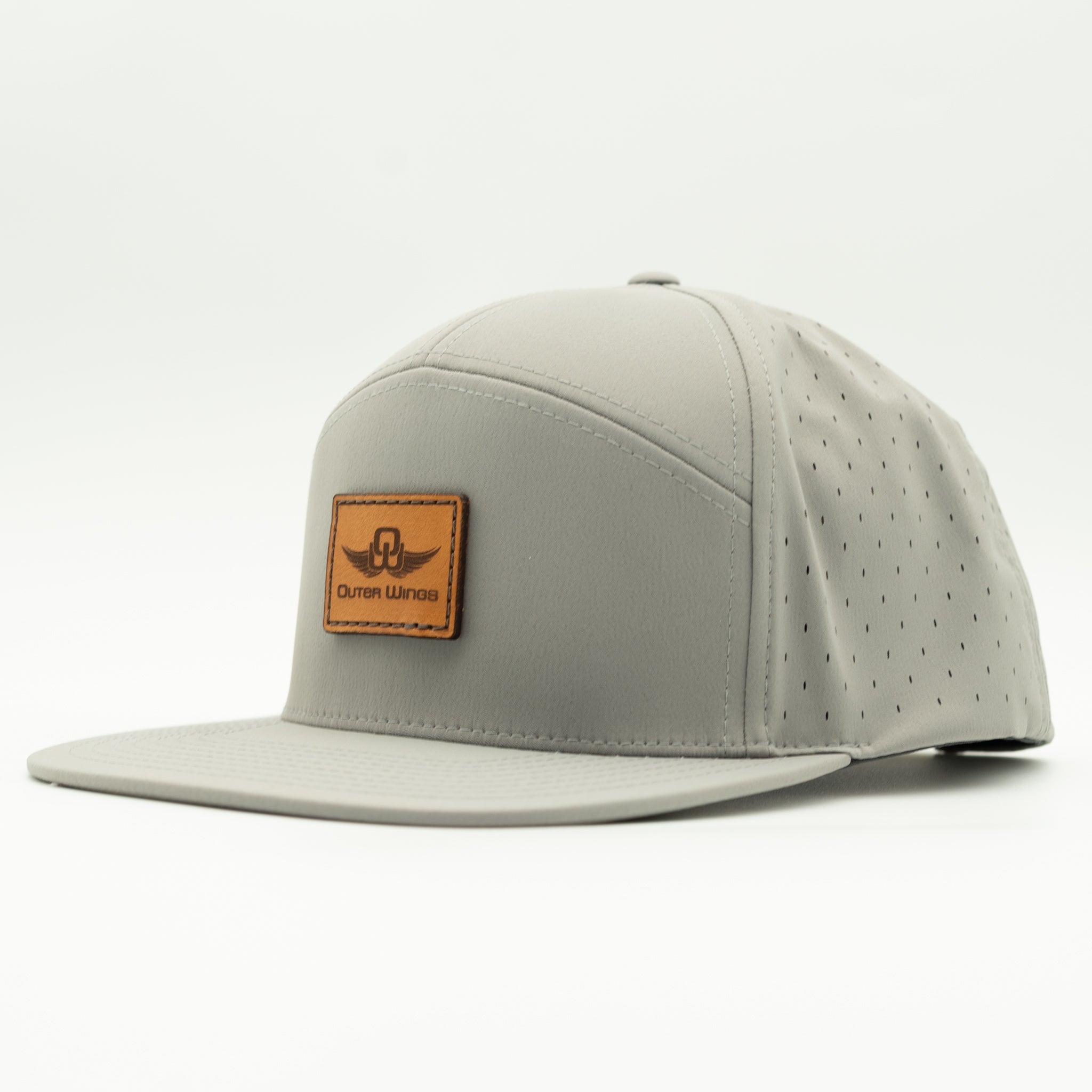 A light gray flat-brim cap with perforated side panels and a brown leather patch on the front displaying the 'Outer Wings' logo, set against a plain white background.

Color: Silver