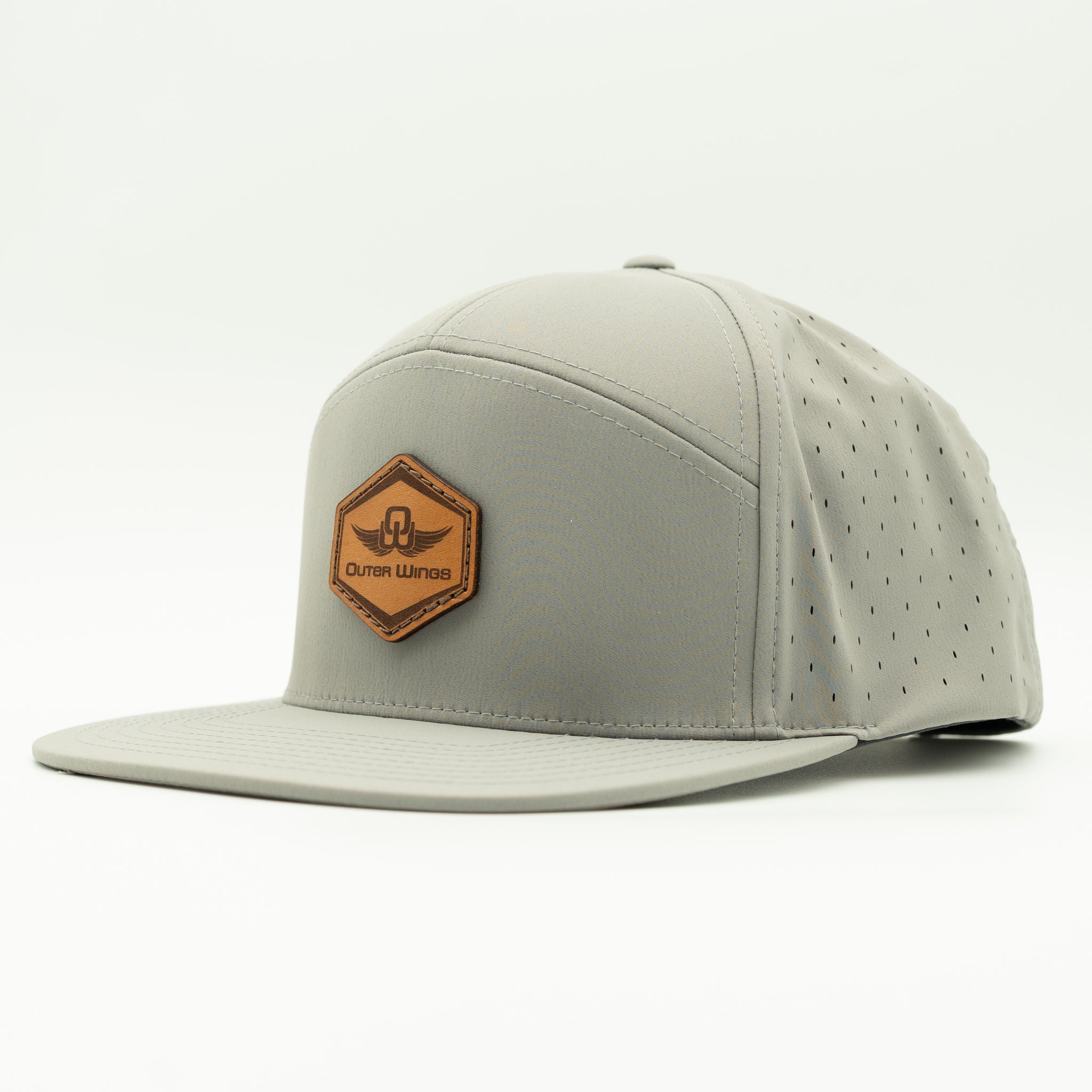 A light gray flat-brim cap with perforated side panels and a brown hexagonal patch on the front that reads 'Outer Wings'.

Color: Silver