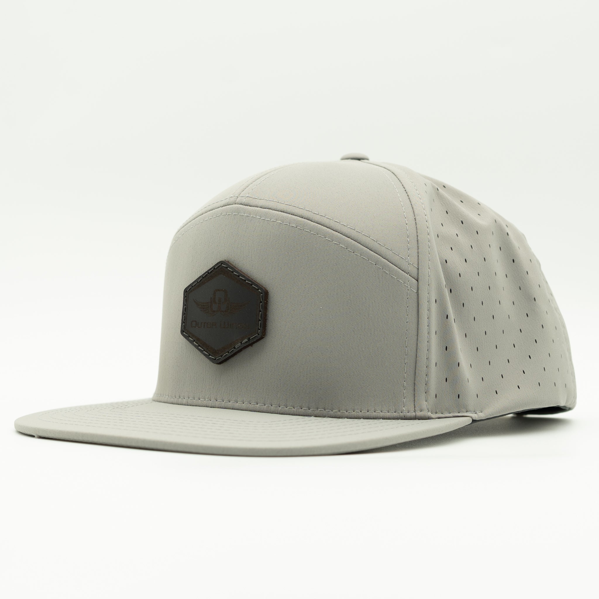 A light gray flat-brim cap with perforated side panels and a dark brown hexagonal patch on the front, photographed on a clean white background.

Color: Silver