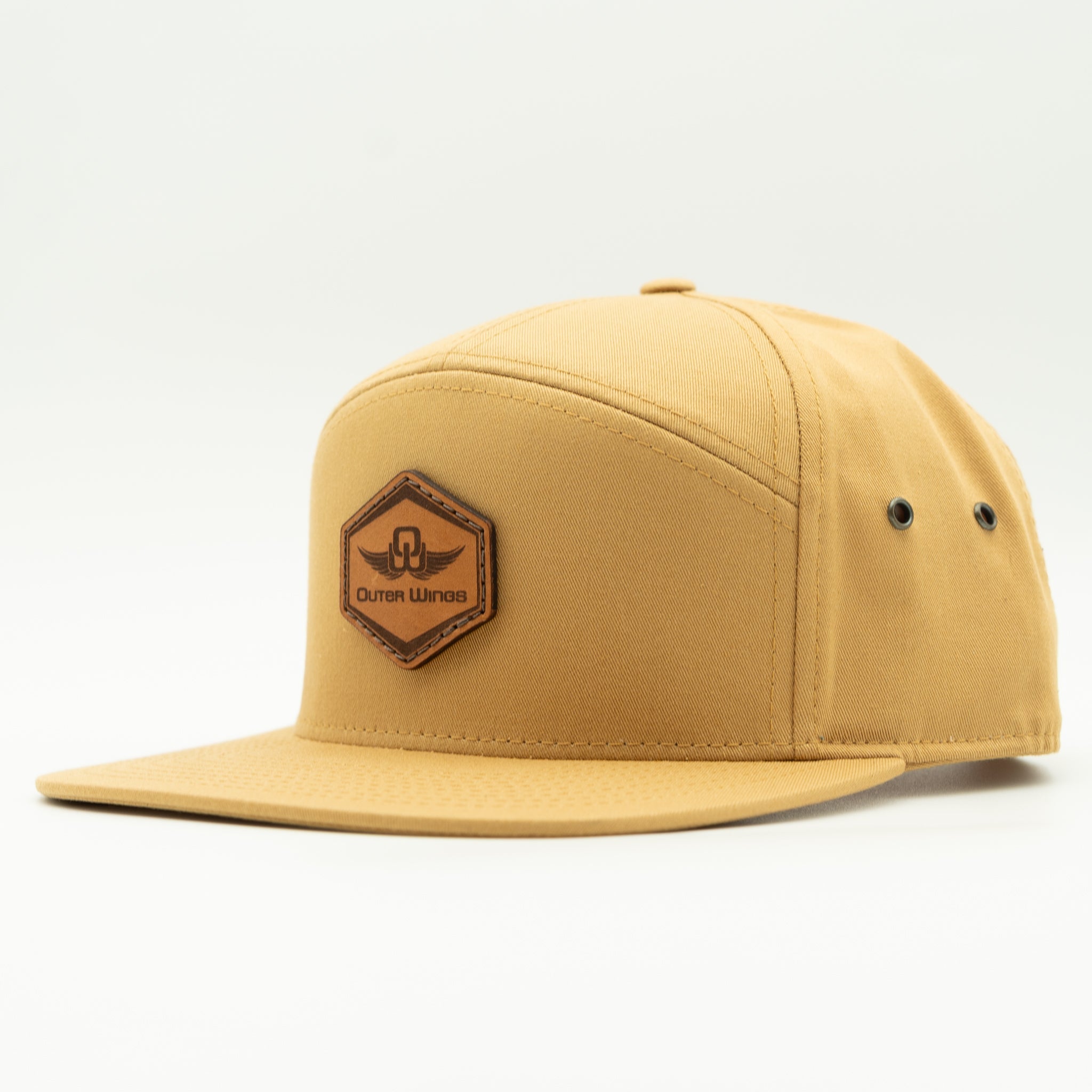 A tan five-panel snapback cap with a flat brim and a brown hexagonal patch on the front that reads 'Outer WIngs'. The cap is photographed on a seamless white studio background.

Color: Biscuit