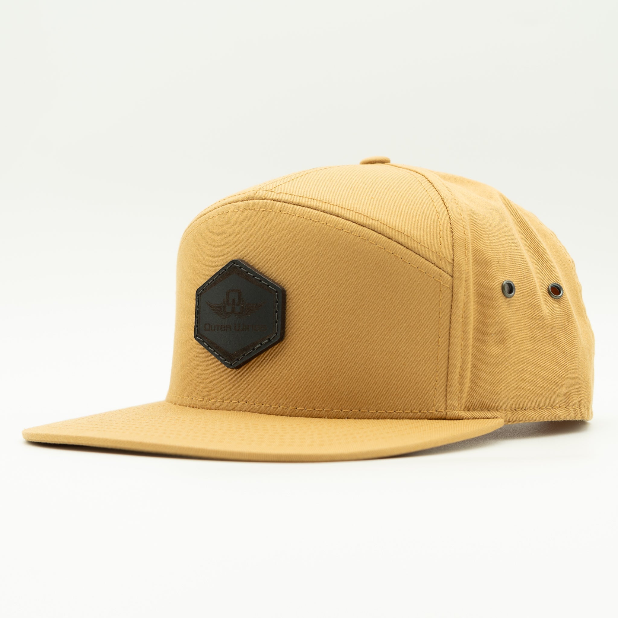 A tan five-panel snapback cap with a black hexagonal patch on the front displaying the brand name 'Outer WIngs'. The cap is photographed from a three-quarters angle against a clean white studio background.

Color: Biscuit