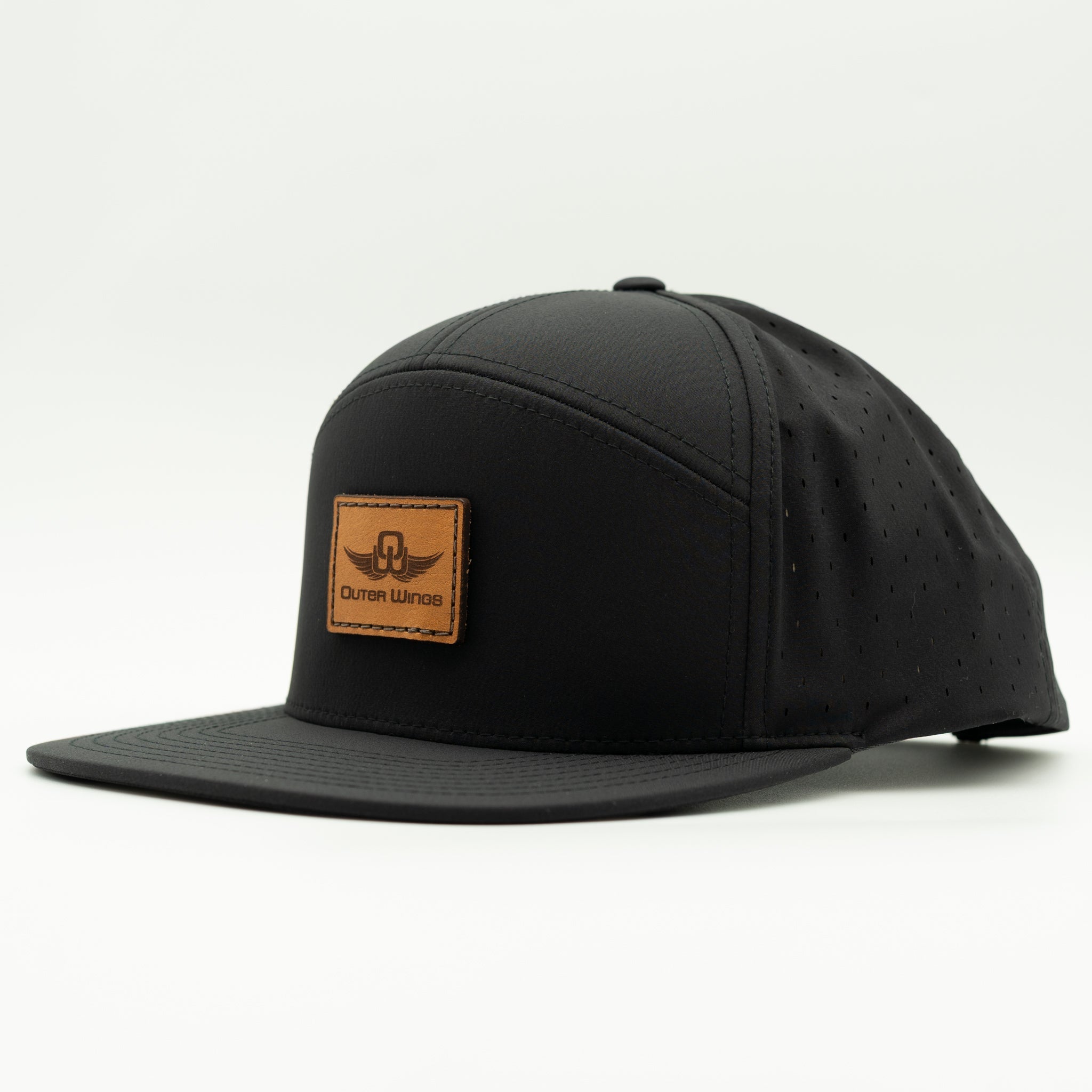 A black flat-brim cap with a tan leather patch on the front displaying the 'Outer Wings' logo, photographed on a clean white background.

Color: Black