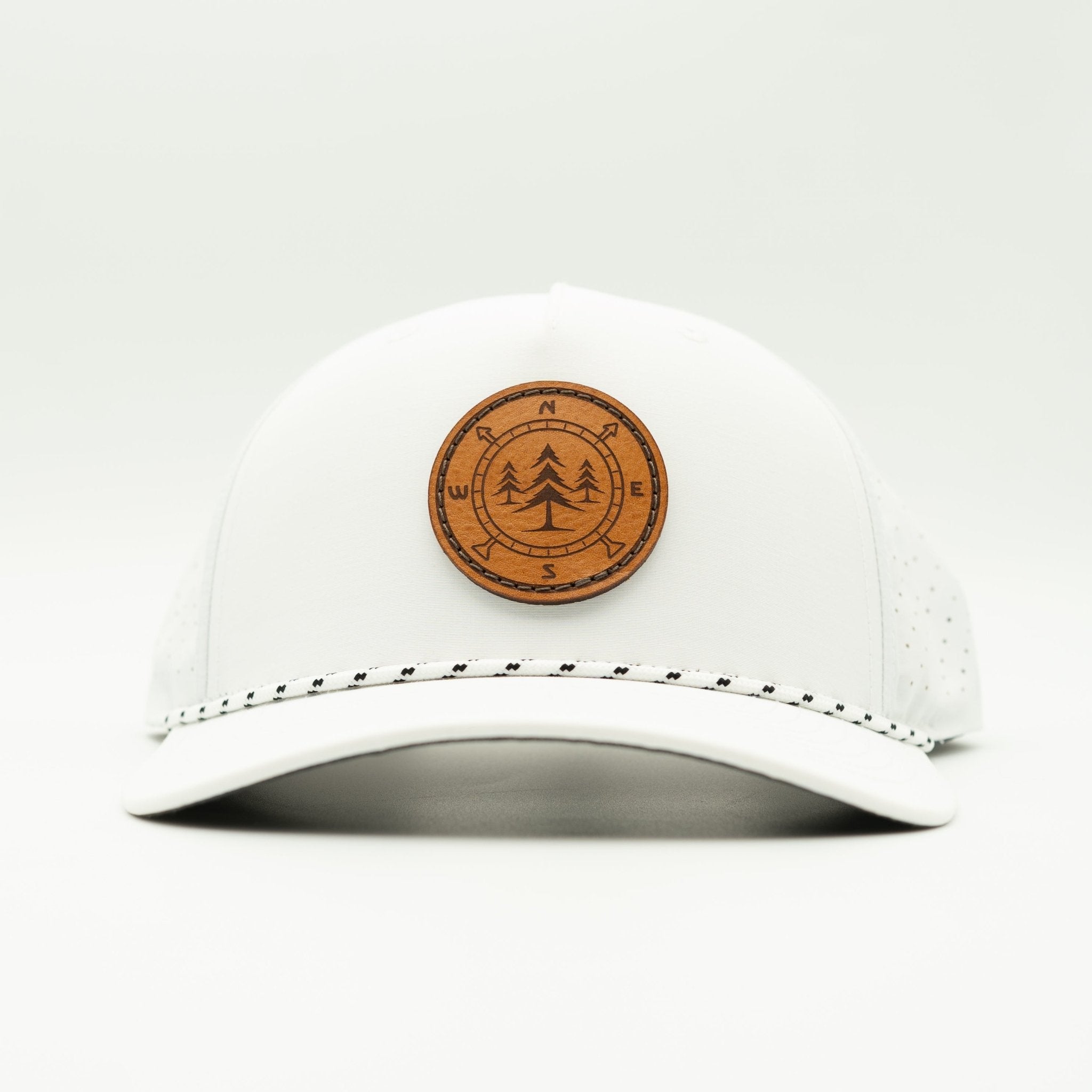 A white trucker-style cap with a brown circular wooden patch featuring a pine tree design on the front, set against a clean white background.

Color: White/Black