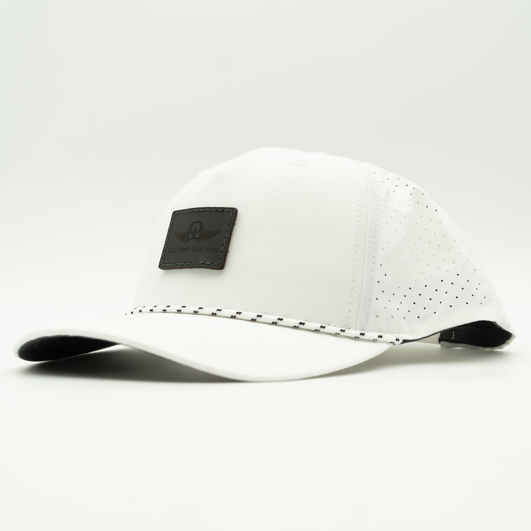 A white baseball cap with perforated back panels, a black leather patch on the front, and a black underside of the brim, photographed on a light gray background.

Color: Solid White