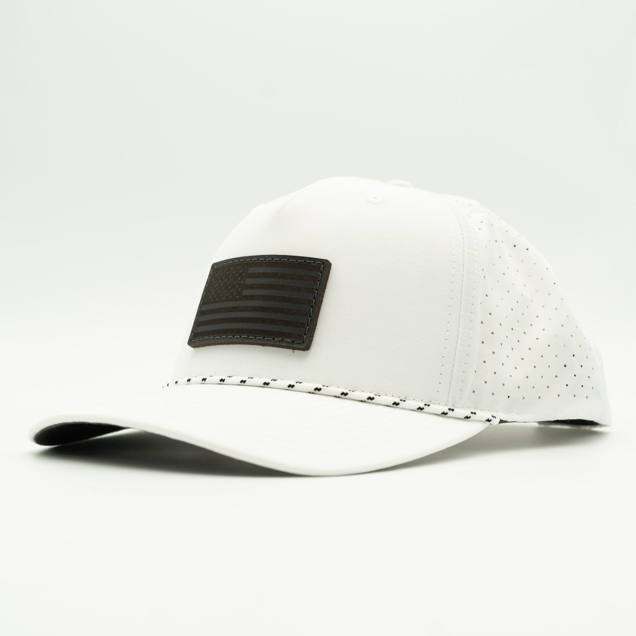 A white baseball cap with a black rectangular American flag patch on the front and a black-and-white dotted line detail along the edge of the brim, shown against a light gray studio background.

Color: White/Black