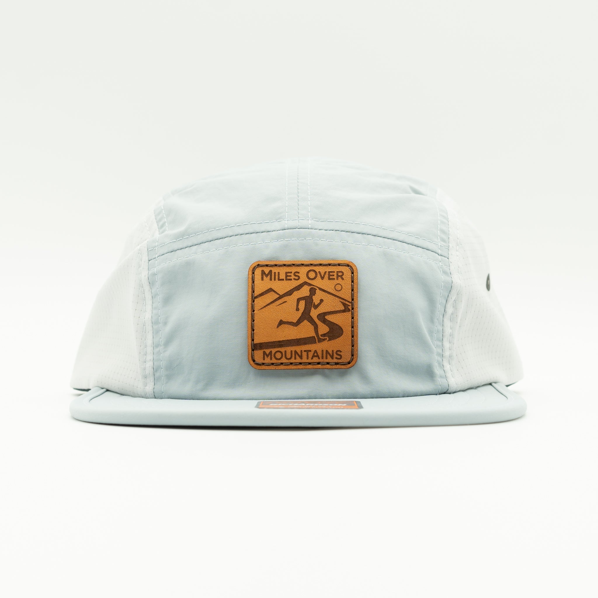A light blue 5-panel cap with a brown leather patch on the front that reads 'MILES OVER MOUNTAINS' with a running mountain climber graphic, shown against a plain white background.

Color: Grey/Glacier Grey