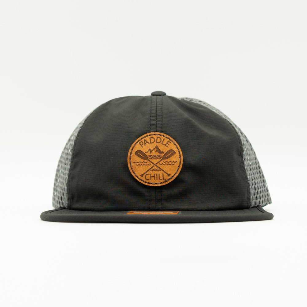 Front view of black and charcoal Paddle and Chill circle leather patch hat, minimalist performance trucker for lakes, rivers and mountain trips.