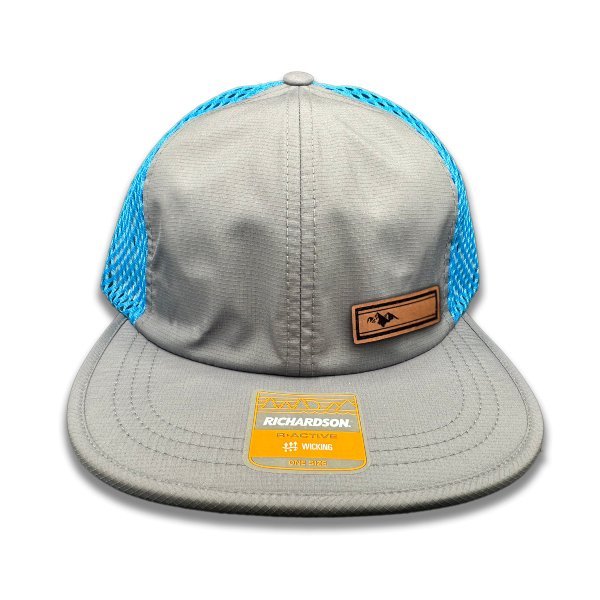 Front view of Richardson 935 hat in charcoal/cyan with Active Mountain leather patch, displaying the mountain design on durable full-grain leather.