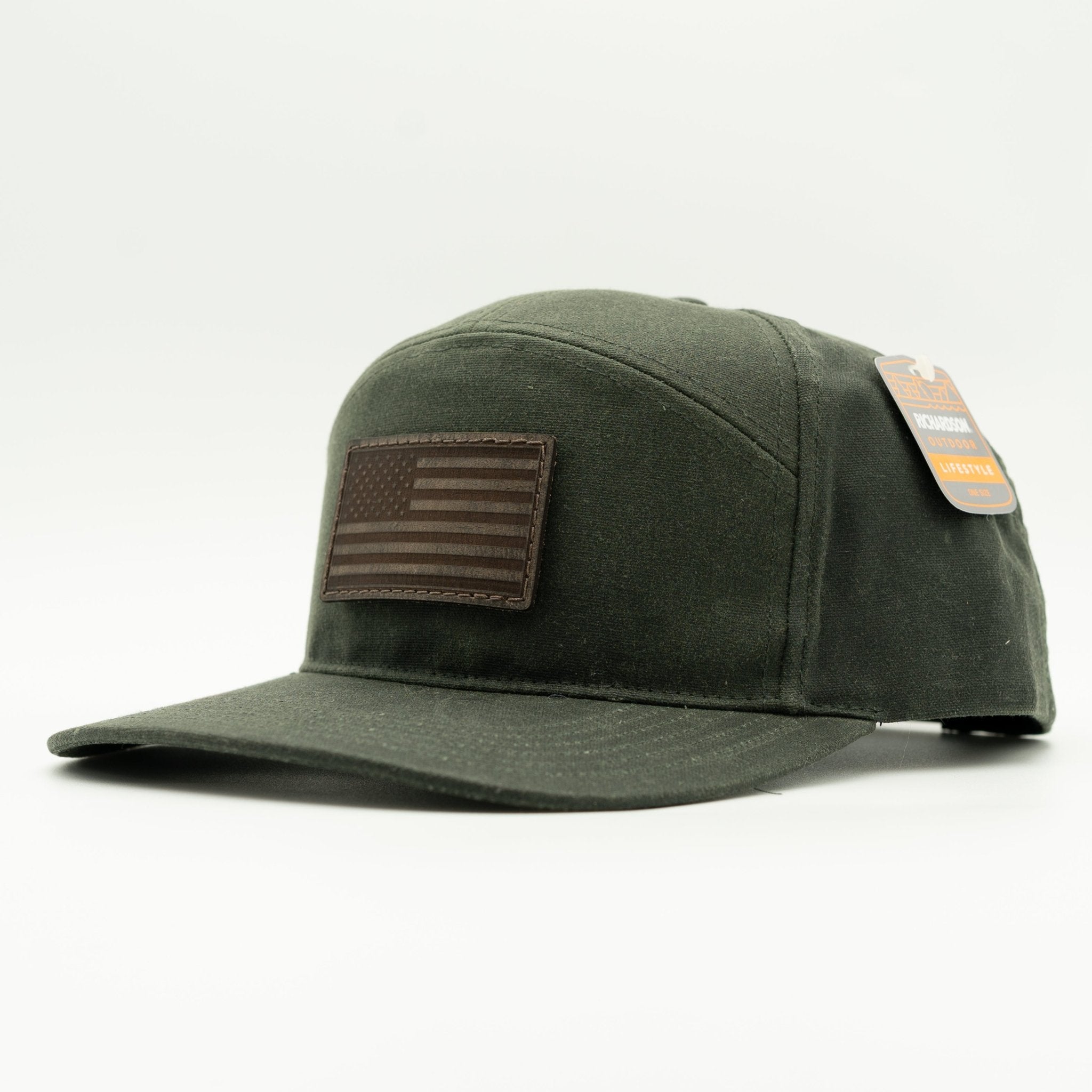 An olive green canvas baseball cap with a brown leather American flag patch on the front, shown on a clean white background with its retail tag still attached.

Color: Dark Olive