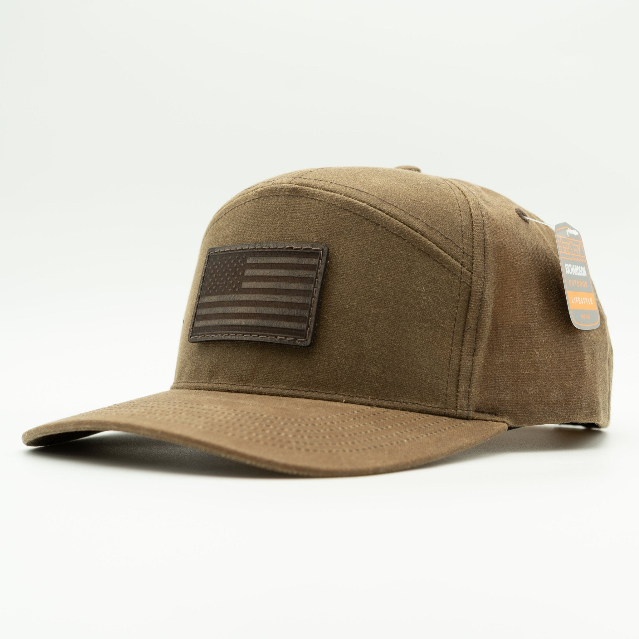 A brown canvas baseball cap with a dark brown American flag patch on the front, shown on a clean white background with a hangtag attached.

Color: Buck