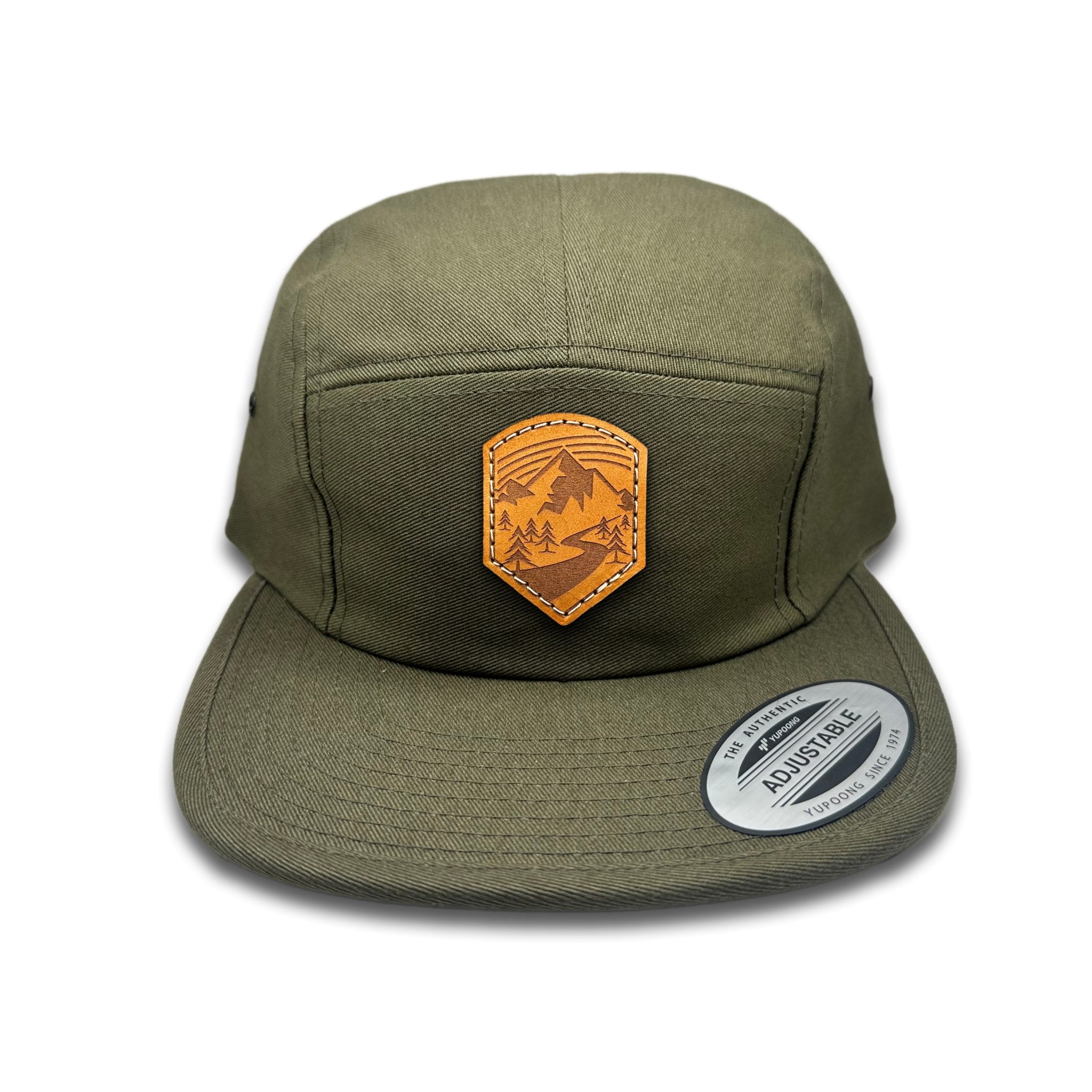 Front view of the Wanderlust Leather Patch Hat by Outer Wings in Olive, featuring a low profile, five-panel Yupoong 7005 flat bill hat with a genuine leather patch showcasing a mountain trailhead design. Perfect for outdoor adventures and casual wear.