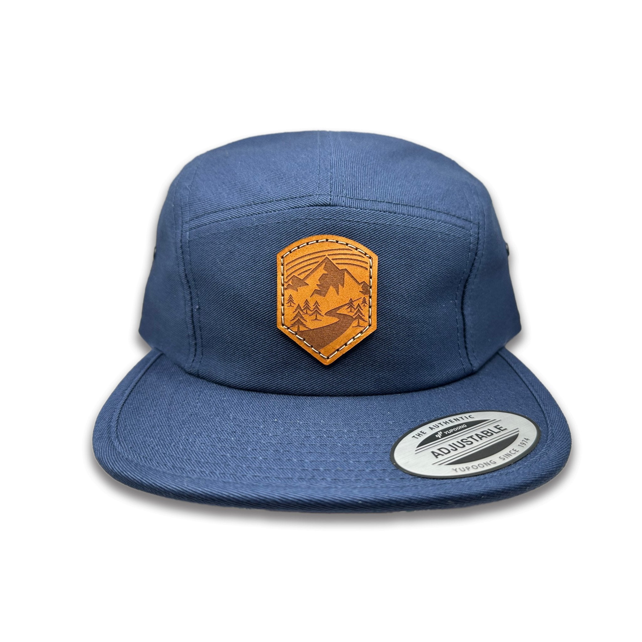 Front view of the Wanderlust Leather Patch Hat by Outer Wings in Navy, featuring a low profile Yupoong 7005 jockey hat with a genuine leather patch featuring a mountain trailhead design. Perfect for outdoor enthusiasts.